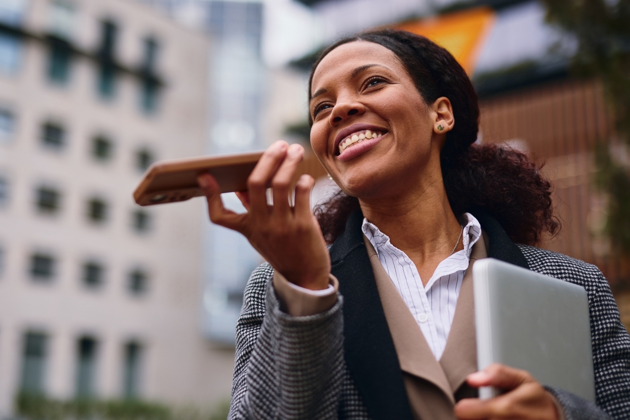 Business woman recording a voice message outdoors on a smart phone | © Igor Suka / E+ / Getty Images